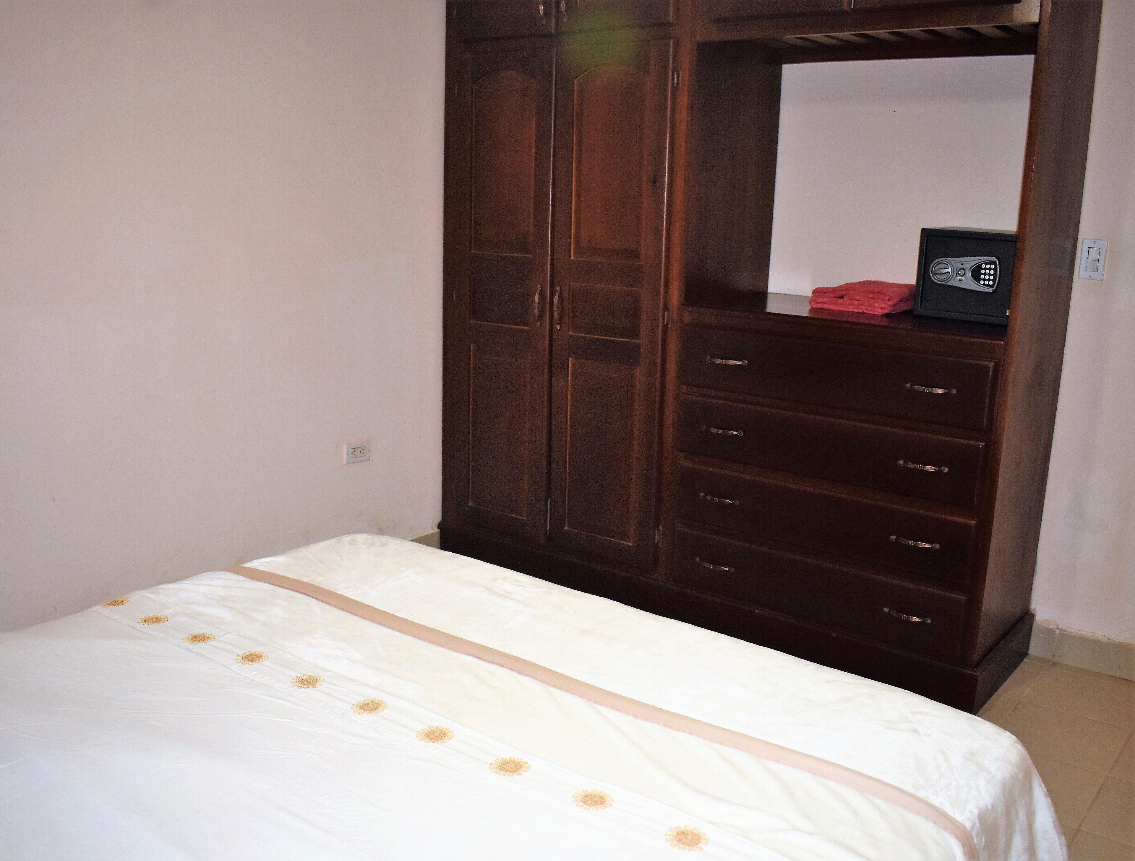 A bedroom with a bed, a wardrobe, and a mirror.