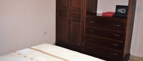 A bedroom with a bed, a wardrobe, and a mirror.