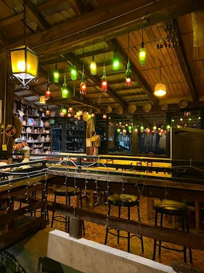 An interior with wooden beams, hanging light fixtures, and a bar area with stools. - Hotel Posada la Escondida (Zacatlán)