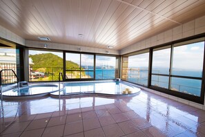 A spacious indoor swimming pool with clear views of the sea and a hilly landscape. - Naruto Kaigetsu Bettei Taimaru Kaigetsu (Naruto)