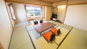 A traditional Japanese room with tatami flooring, a low table with cushions, a television, and a view of the sea through large windows. - Naruto Kaigetsu Bettei Taimaru Kaigetsu (Naruto)