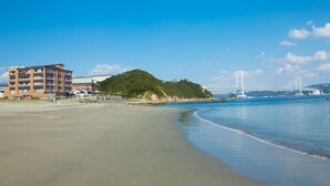 A beach with a large building and a bridge in the background. - Naruto Kaigetsu Bettei Taimaru Kaigetsu (Naruto)