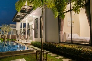 Un hotel moderno con piscina, una escalera que conduce al piso superior y un jardín bien cuidado.
