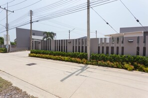 Een modern gebouw met een hekpoort, een verharde weg en betonnen palen met elektrische kabels.