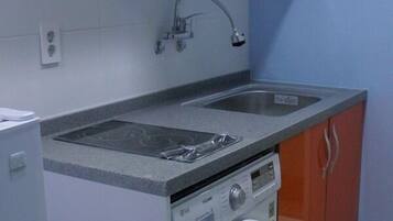 A compact kitchen with a washing machine, a stove, and a sink.