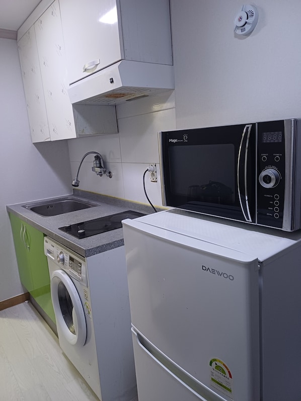 A compact kitchen with a washing machine, a microwave, and a sink.