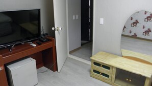 A room with a TV on a wooden desk, a small fridge, a wooden bed with a headboard, and a door leading to another room. - Good Morning Vil Residenece Inn (Gumi)
