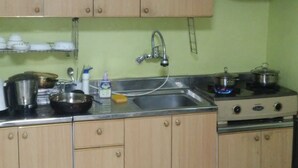 A kitchen with wooden cabinets, a stainless steel sink, and a gas stove. - Good Morning Vil Residenece Inn (Gumi)