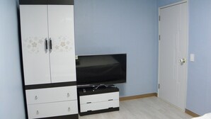 A room with a TV on a stand, a wardrobe with floral patterns, and a door. - Good Morning Vil Residenece Inn (Gumi)