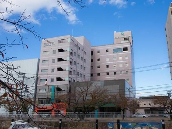 Un edificio de varios pisos con fachada plana, varias ventanas y una señal visible en la parte superior.