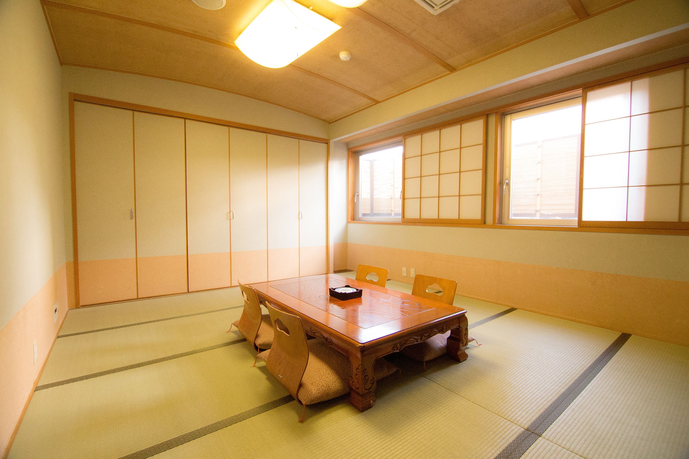 Une pièce de style japonais traditionnel, avec un sol recouvert de tatamis, une table en bois et des portes coulissantes.
