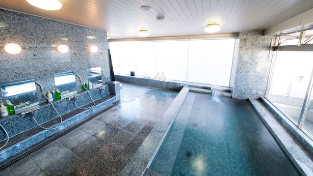 Un baño moderno con encimeras de granito, cabina de ducha con mampara de vidrio y un amplio ventanal que aporta luz natural.