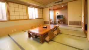 Una habitación japonesa tradicional con suelo de tatami, una mesa de comedor de madera y puertas correderas.