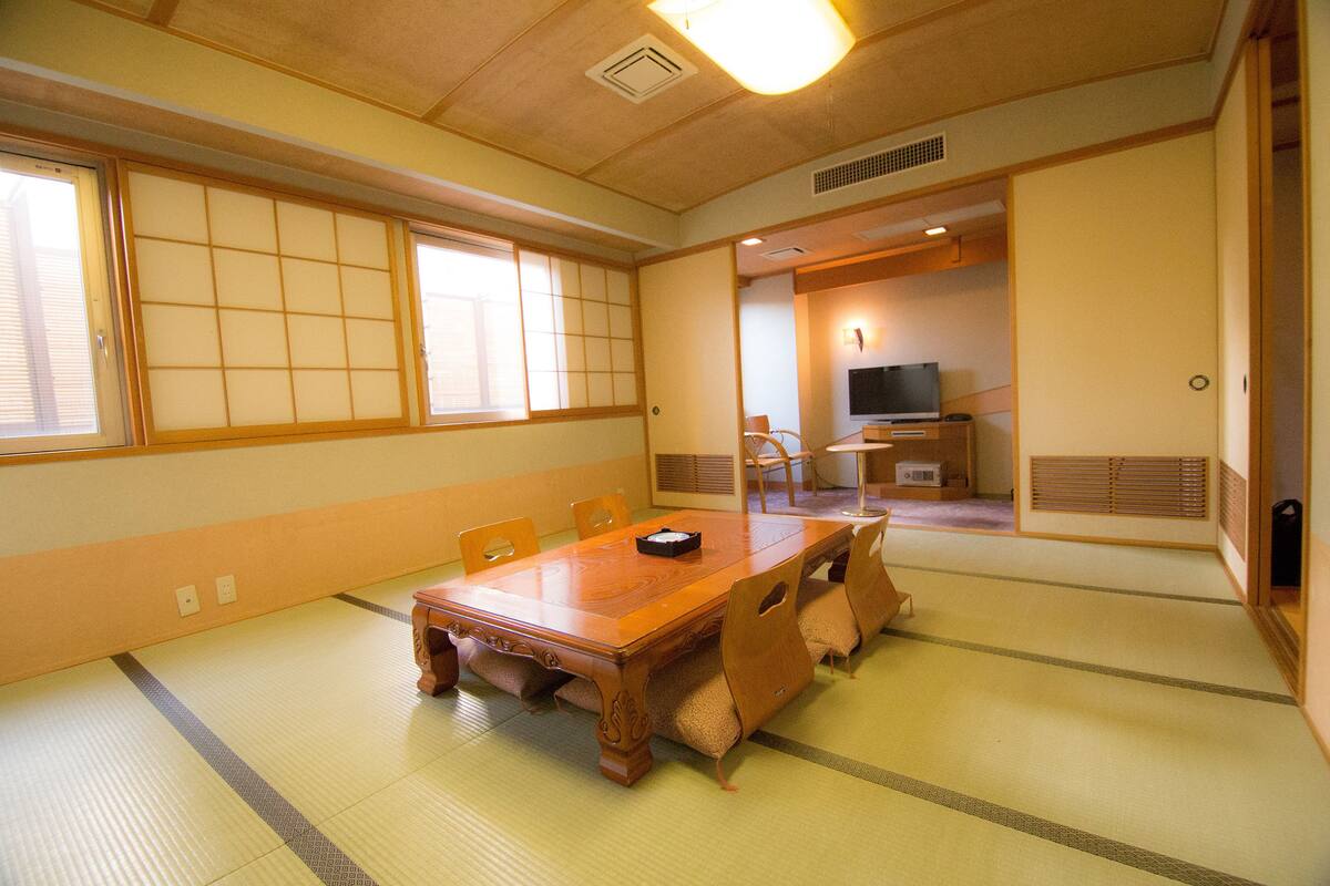 A traditional Japanese room with tatami flooring, a wooden dining table, and sliding doors.
