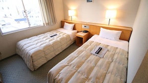 Habitación de hotel con dos camas individuales, una ventana con cortinas, lámparas de noche, una mesita y un teléfono instalado en la pared.