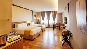Quarto de hotel com uma cama grande, uma escrivaninha, uma cadeira, uma televisão e um aparelho de café.