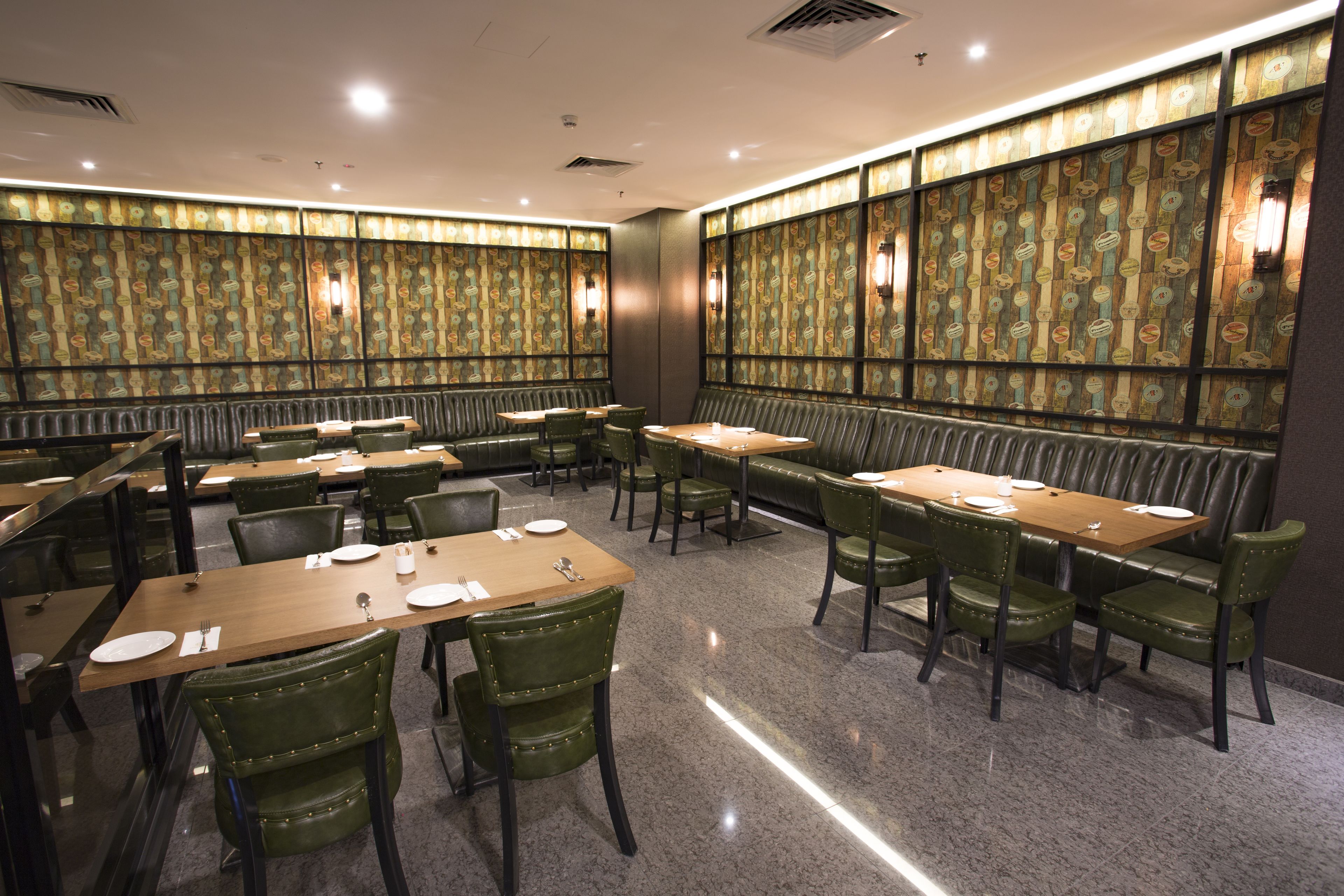 A restaurant with multiple tables and booths, arranged in a spacious layout with a patterned wall design.