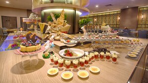 Buffet com diversos doces e bebidas, incluindo um bolo grande e vários copinhos de sobremesa.