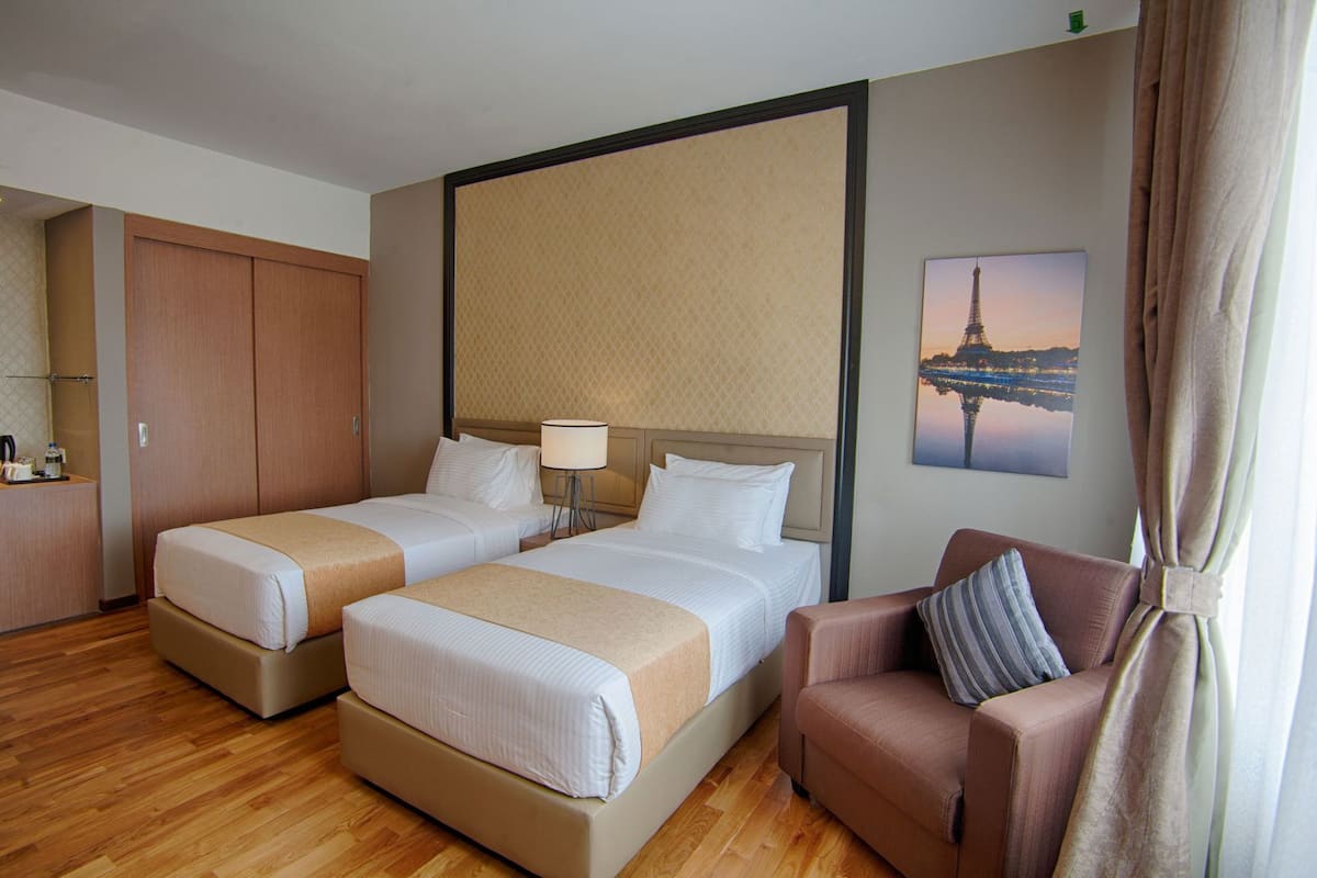 A hotel room with two beds, a sofa, a desk, and a view of the Eiffel Tower.