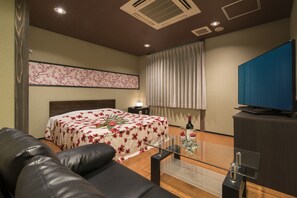 A hotel room with a bed, a sofa, a glass coffee table, a television, and a window with curtains. - Hotel Wacha Wacha - Adults Only (Kyoto)
