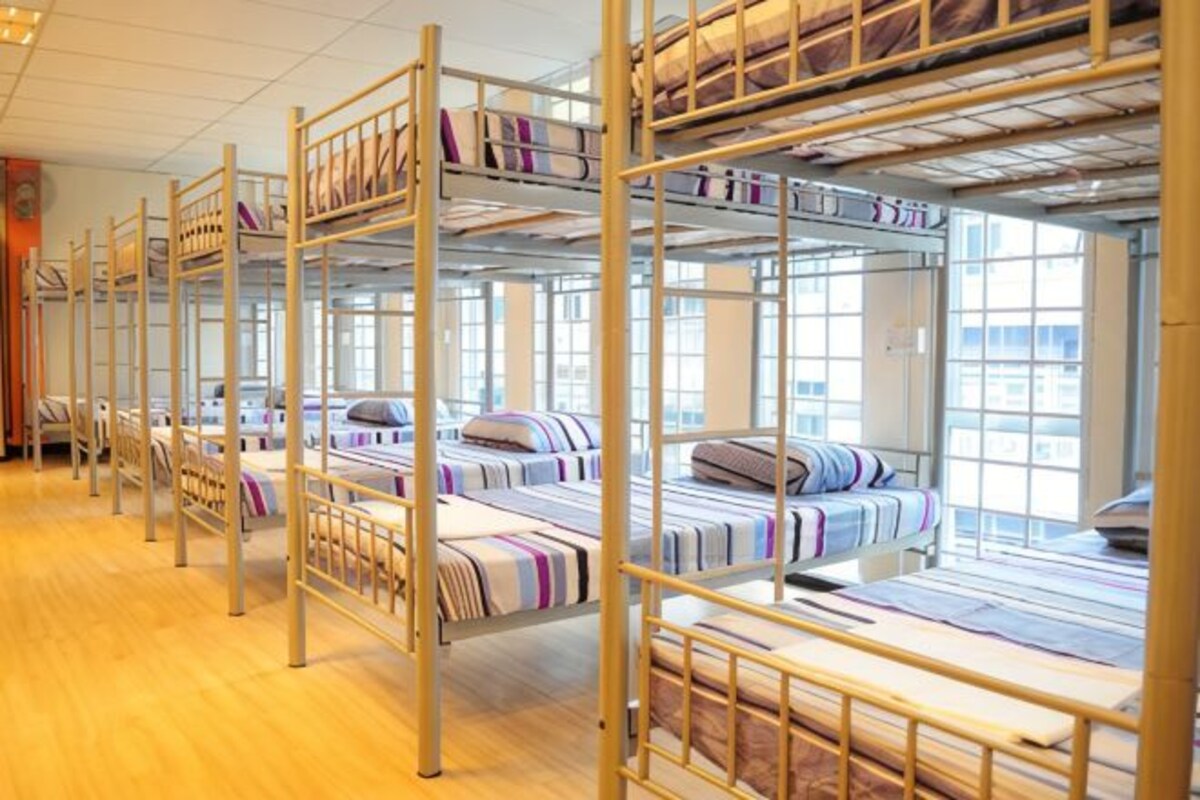 Bunk beds with striped bedding, wooden floors, and large windows.