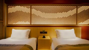 A hotel room with two beds, a wooden headboard, a small nightstand, and a decorative screen.