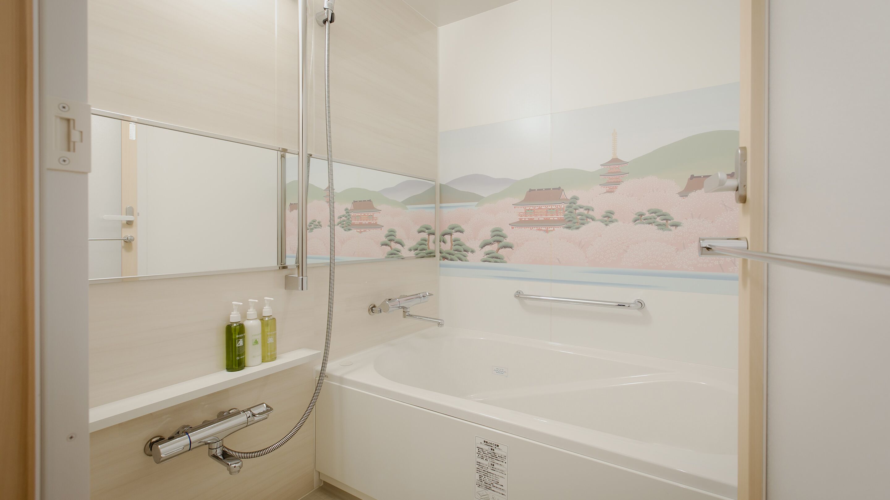 A modern bathroom with a bathtub, a shower, and a mirror. There are toiletries on the shelf.