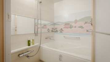 A modern bathroom with a bathtub, a shower, and a mirror. There are toiletries on the shelf.