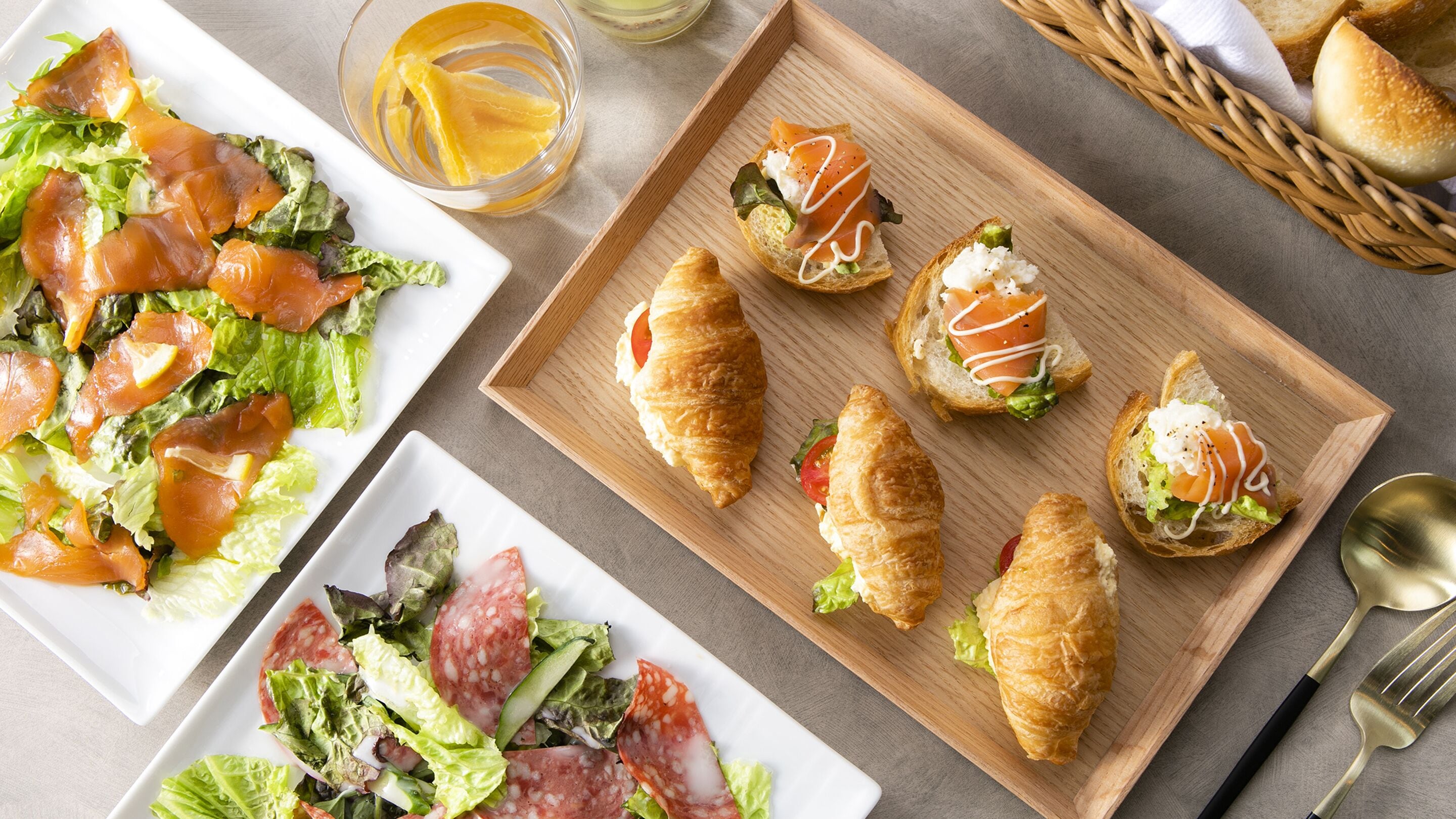 Diversos alimentos, como ensalada, croissants y un plato con salmón ahumado.