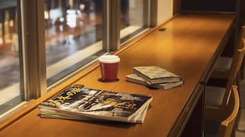 A wooden bench with a magazine, a coffee cup, and a stack of books.