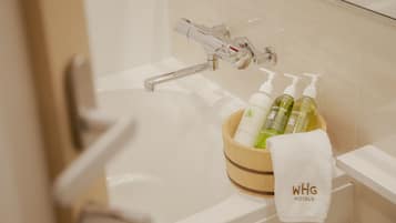 Uma banheira com produtos de higiene, incluindo um frasco de condicionador, sabonete líquido e shampoo, e uma toalha com a inscrição "WHG HOTELS".