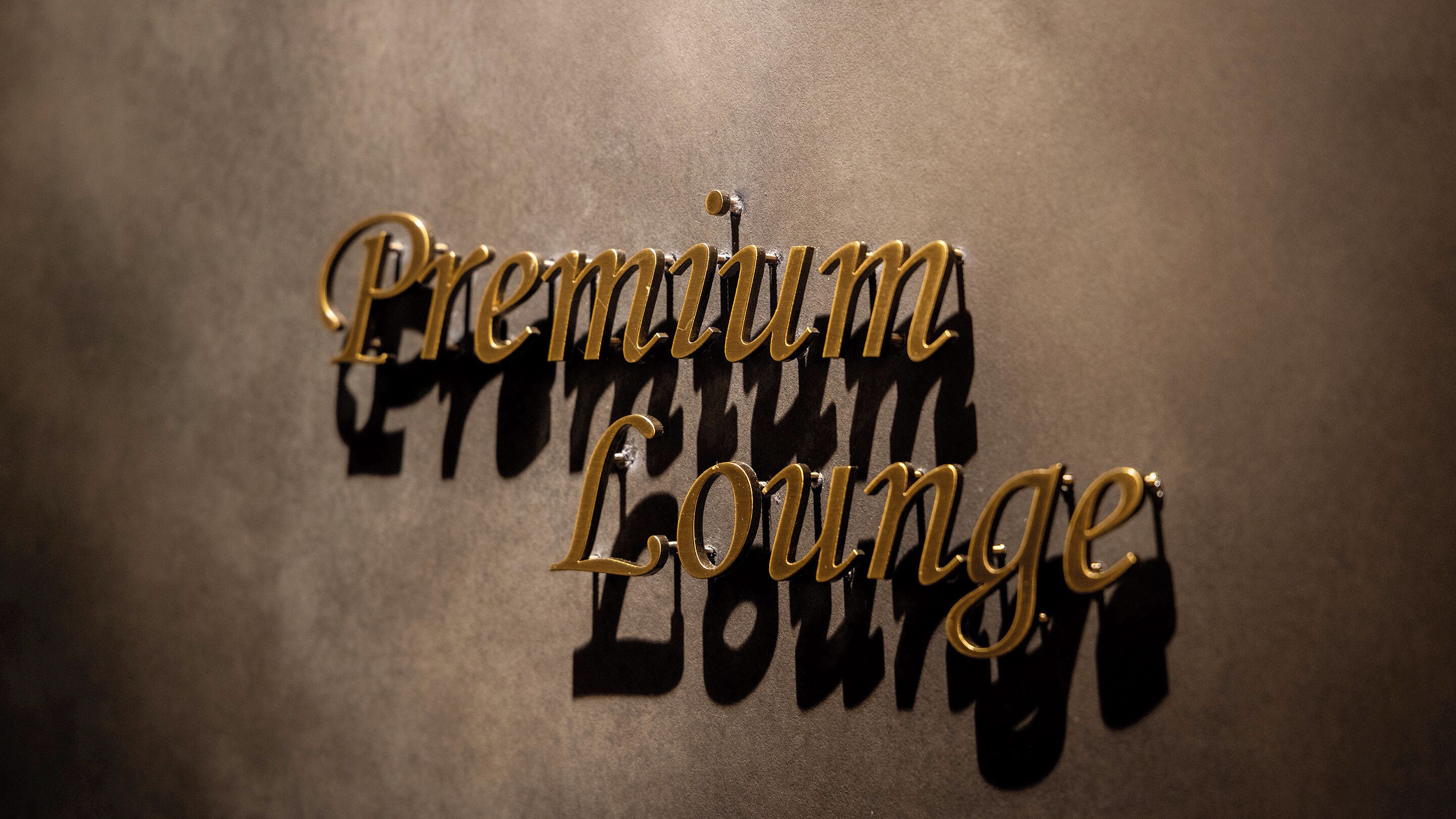 A wall with the words 'Premium Lounge' in a decorative font.