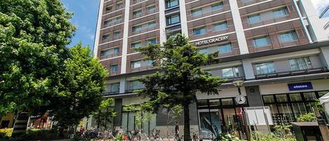 Un hotel de varios pisos con diseño moderno, que cuenta con un patio central y escalones que conducen a la entrada.