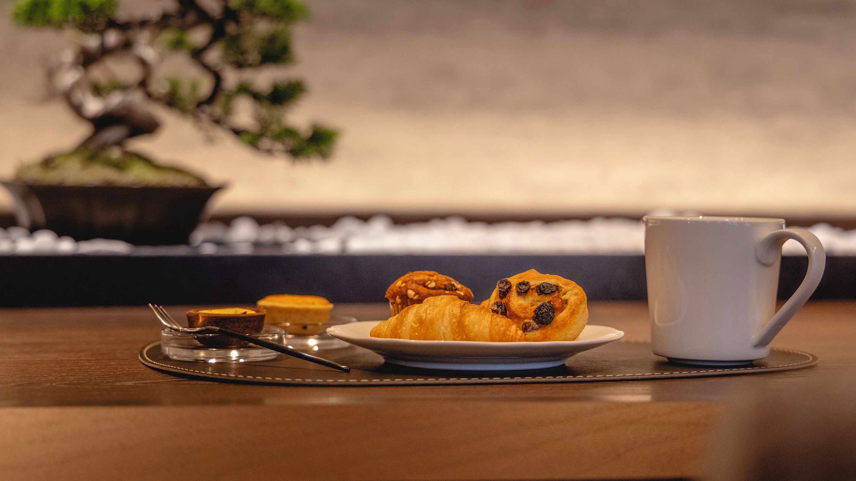 A table with pastries, a cup, and a keyboard in the background.
