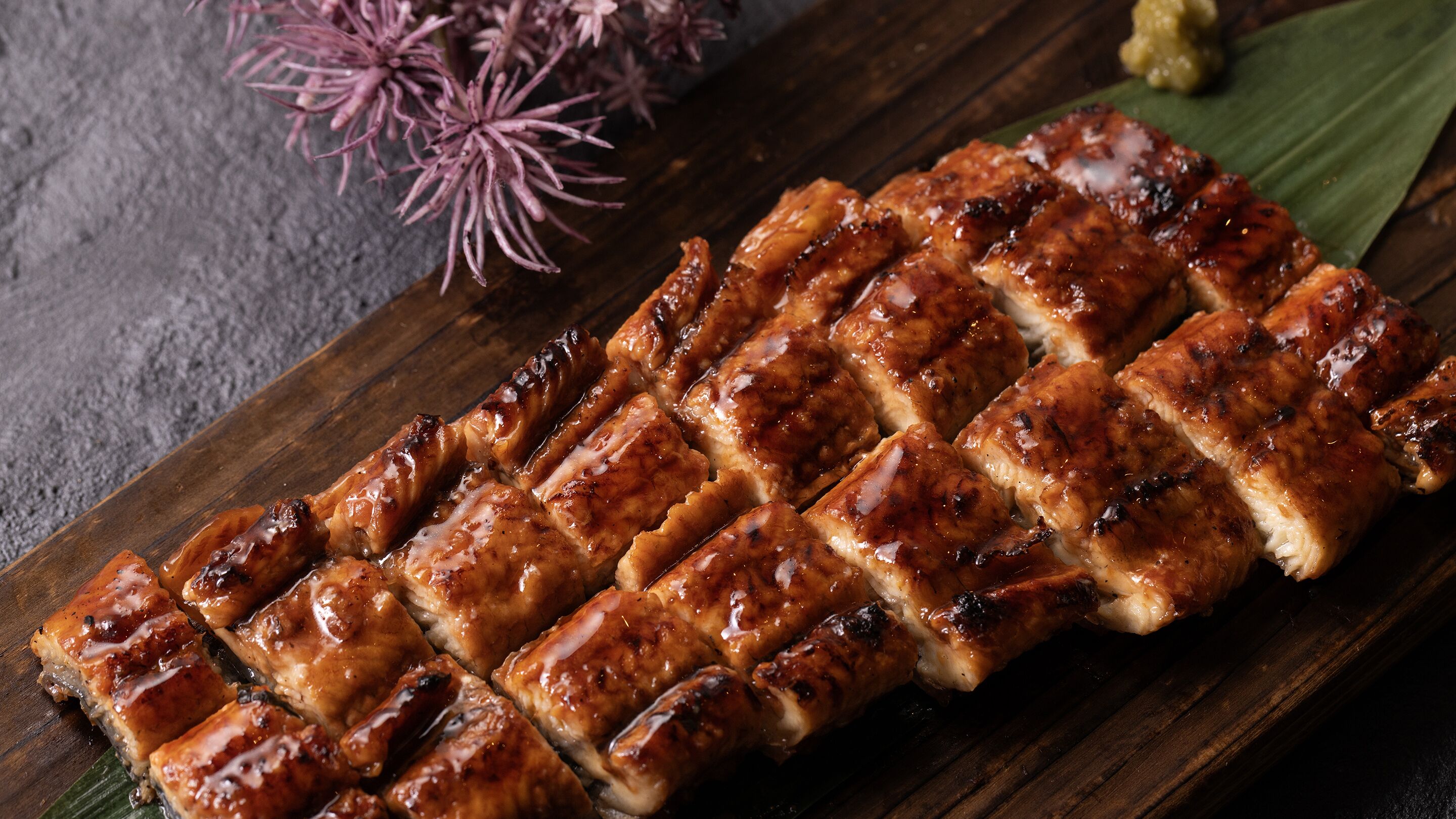 Ein Holzschnittbrett mit in Gitterform angeordneten gegrillten Fleischscheiben.