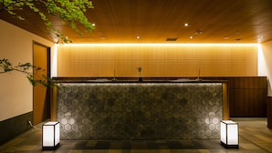A reception area with a honeycomb-patterned wall, a wooden reception desk, and two standing lamps.