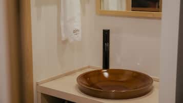 A bathroom with a brown ceramic sink, a black faucet, and a white towel hanging on the wall.