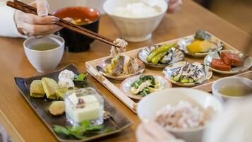 Variedad de platos japoneses sobre una mesa de madera, incluyendo sushi, sashimi y otras comidas tradicionales, con palillos y cuencos de sopa.