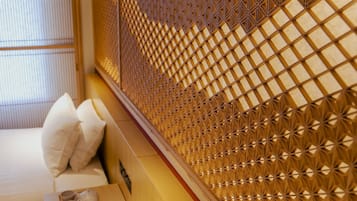 A room with a traditional Japanese-style sliding door, a bed with white bedding, and a small table with a teapot.
