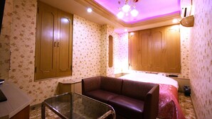 Quarto com papel de parede floral, cama, sofá e escrivaninha.
