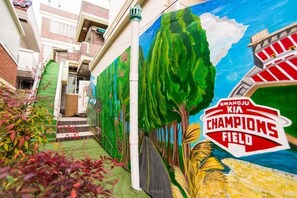A mural of a lush landscape with trees and a stadium labeled "GWANGJU KIA CHAMPIONS FIELD". - Pedro's House - Hostel (Gwangju)