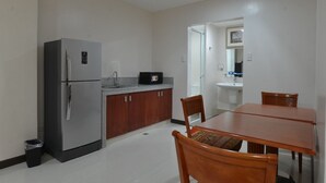 Una cocina compacta con refrigerador, un lavamanos y una mesa de comedor con sillas.