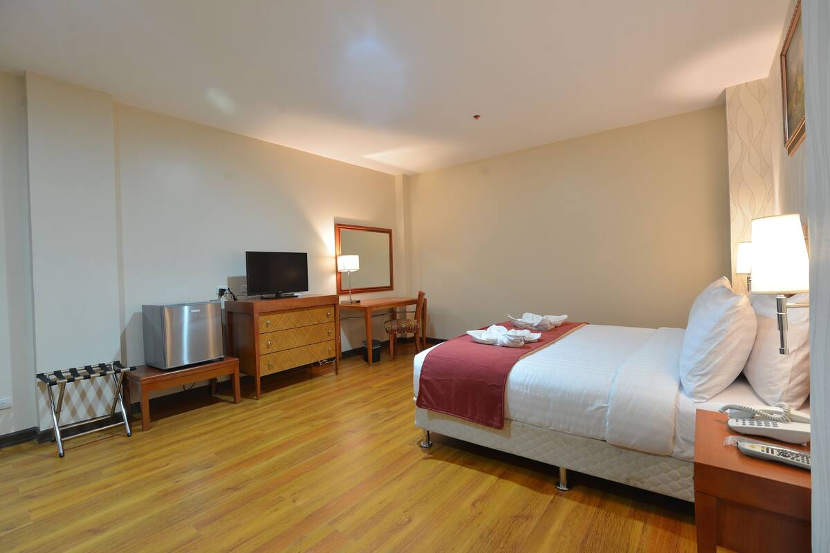 A hotel room with a bed, a desk, a television, a telephone, and a lamp.
