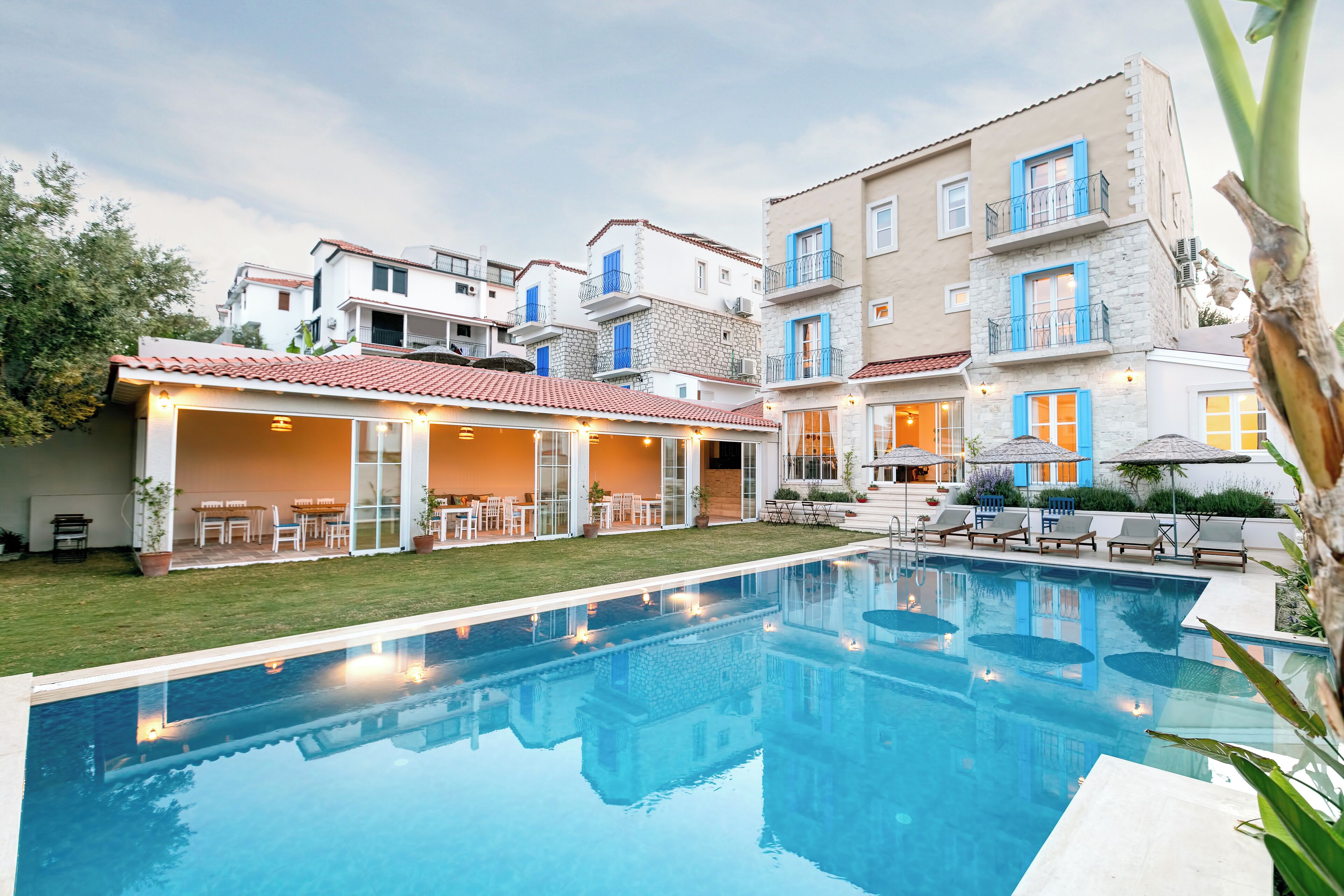 A swimming pool with a covered patio area, surrounded by multi-story buildings with balconies and outdoor seating.