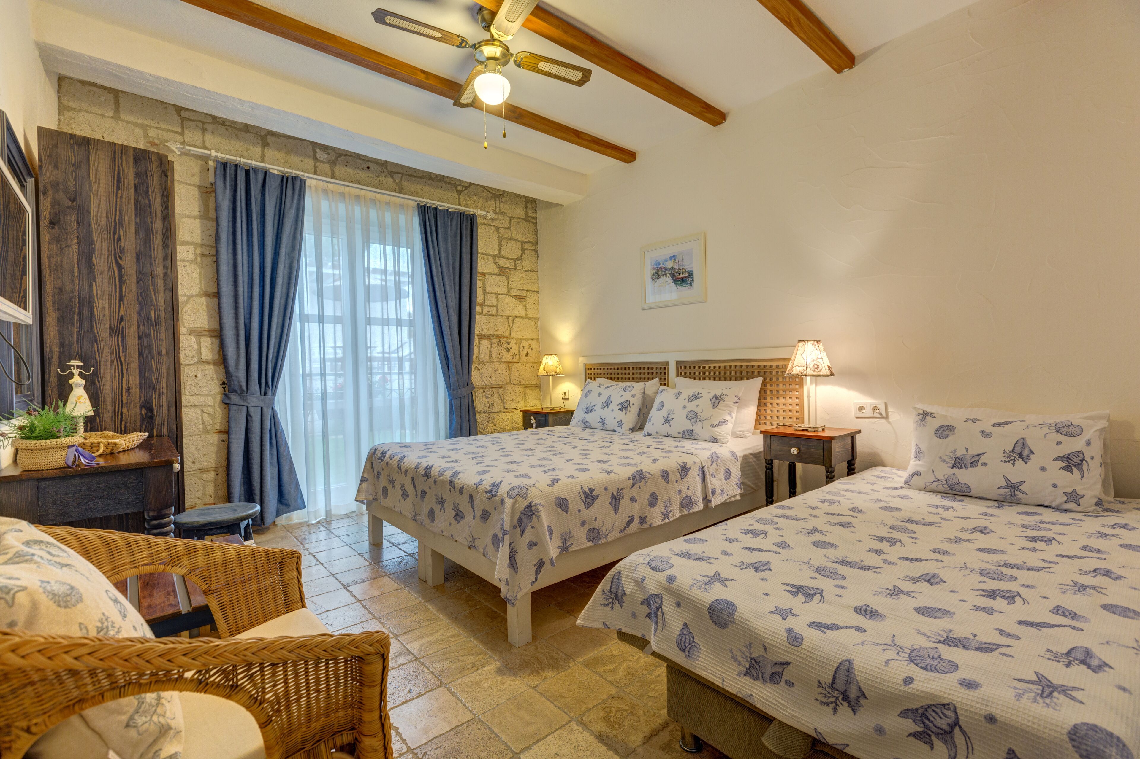 Une chambre avec deux lits, un mur en pierre, un plafond en bois et une fenêtre avec des rideaux.