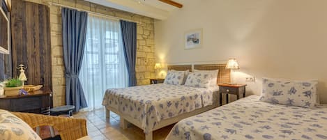 Une chambre avec deux lits, un mur en pierre, un plafond en bois et une fenêtre avec des rideaux.