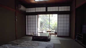 A traditional Japanese-style room with tatami flooring, a low table, and a bed with a futon. - Ryokan Yamamuro (Kanazawa)