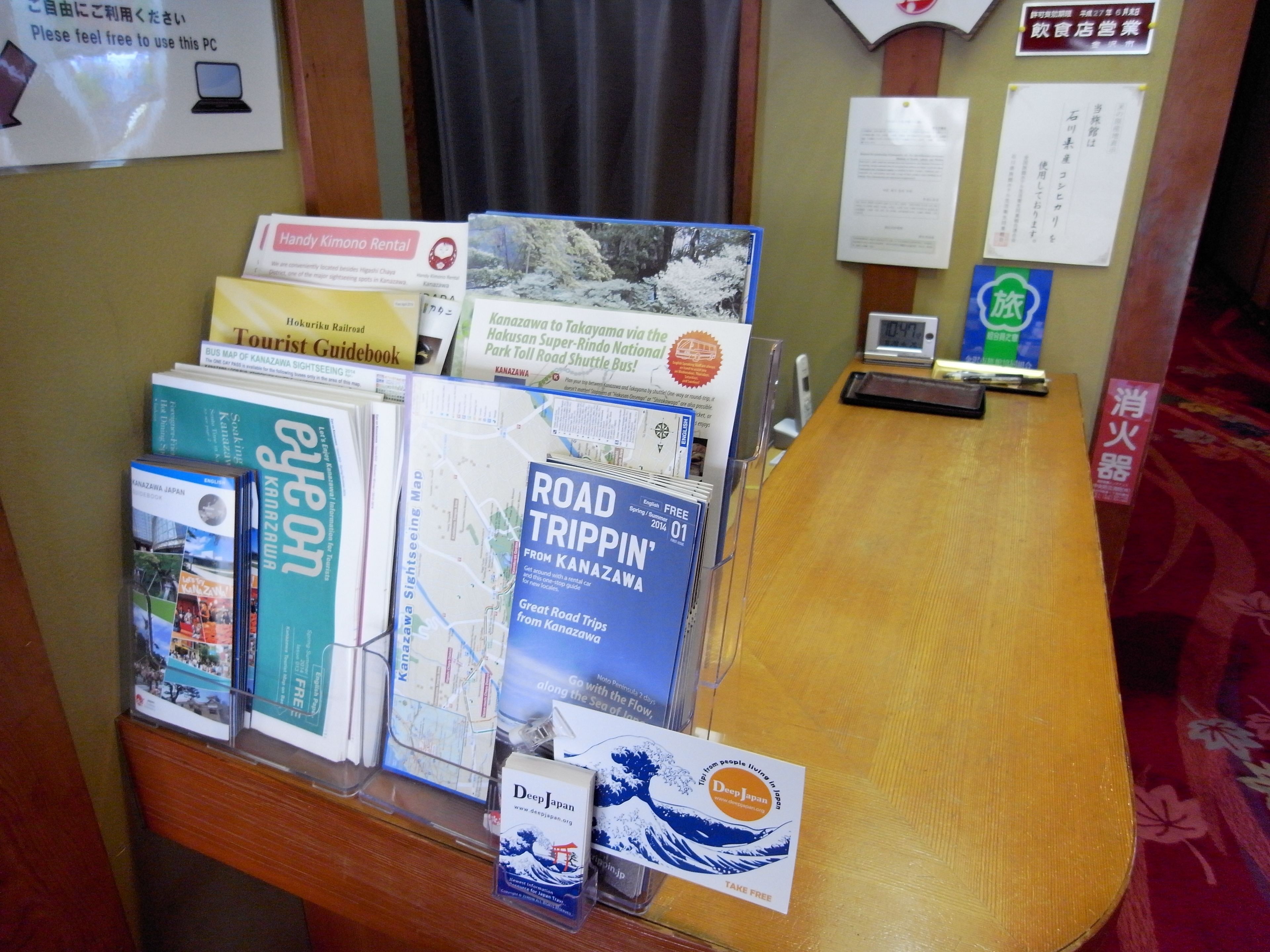 A desk with various travel guides and maps, including 'Road Tripping' and 'Kanazawa Sightseeing'.