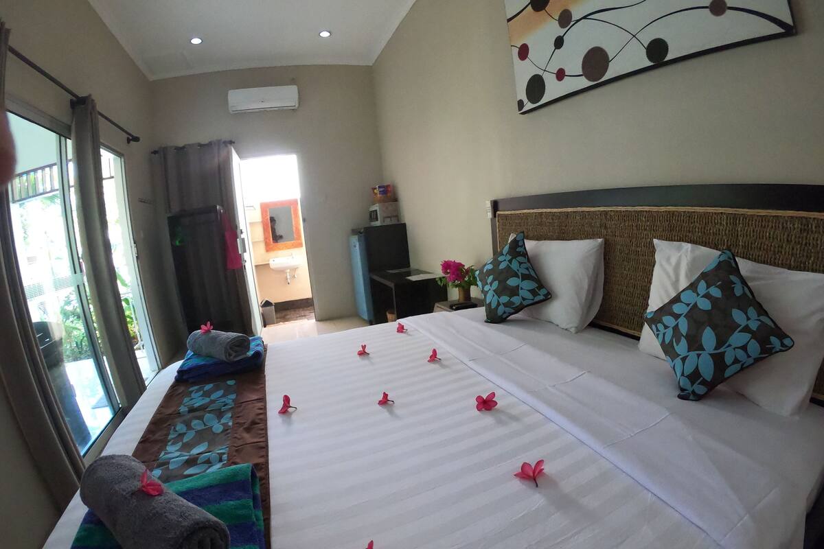 A hotel room with a large bed, a bedside table, a TV, and a view of the outside.