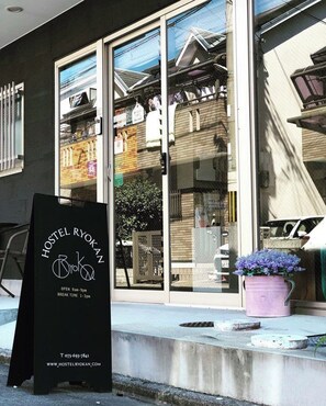 A hostel with a glass facade, a signboard, and a potted plant. - Kyoto Hostel Ryokan (Kyoto)